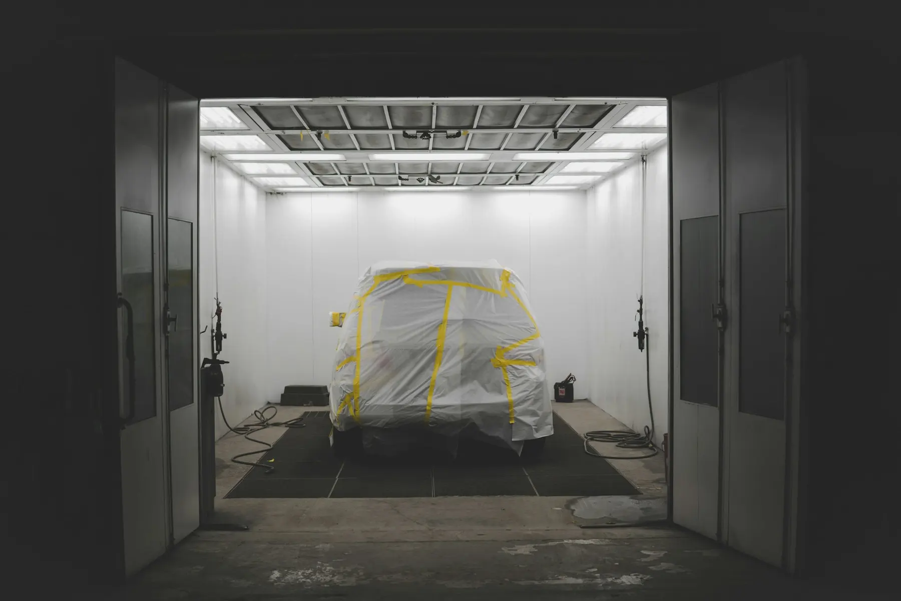 A masked car standing in a sealed spray booth ready for paint