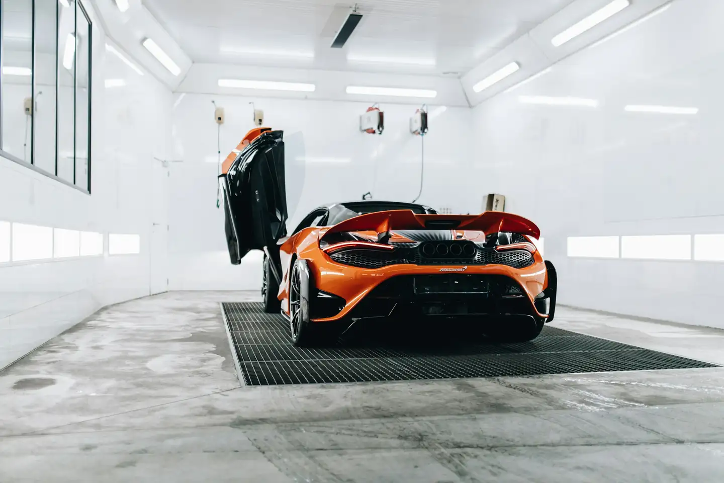 A car with its bonnet open under the lights of a paint booth