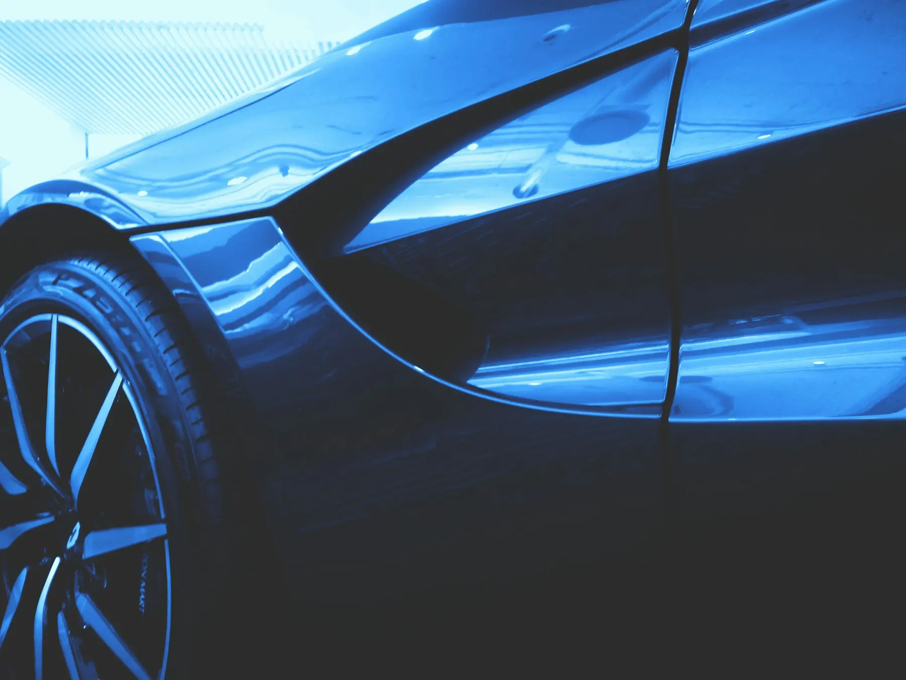 The flank of a car catching a hard highlight along its shoulder line