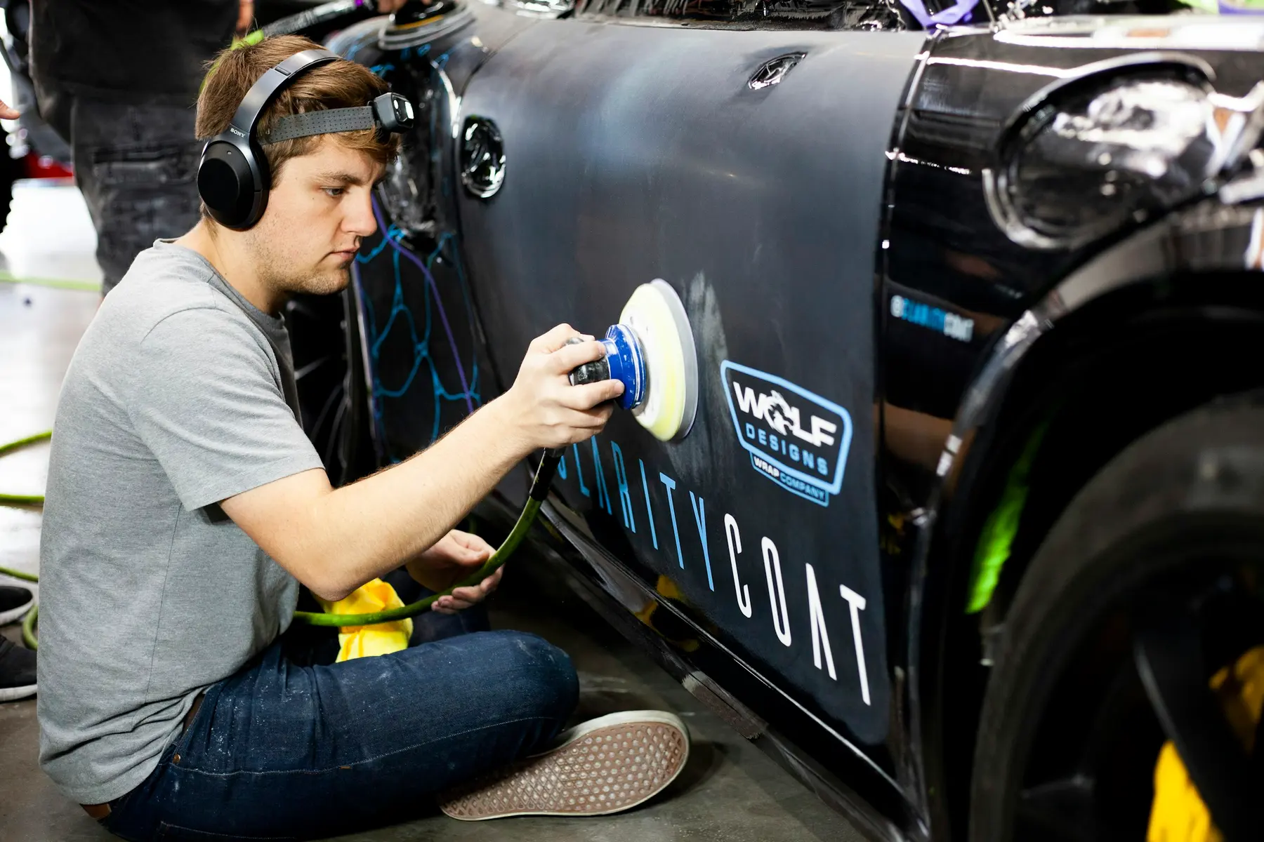 A finished car being polished by hand under workshop light